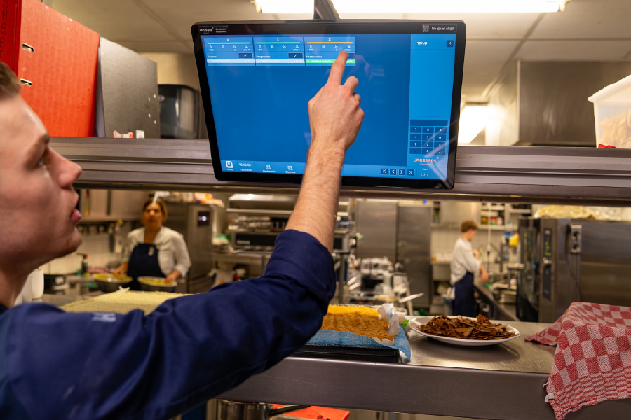 Personeel geeft order door op een keukenscherm in Kasteel Maurick